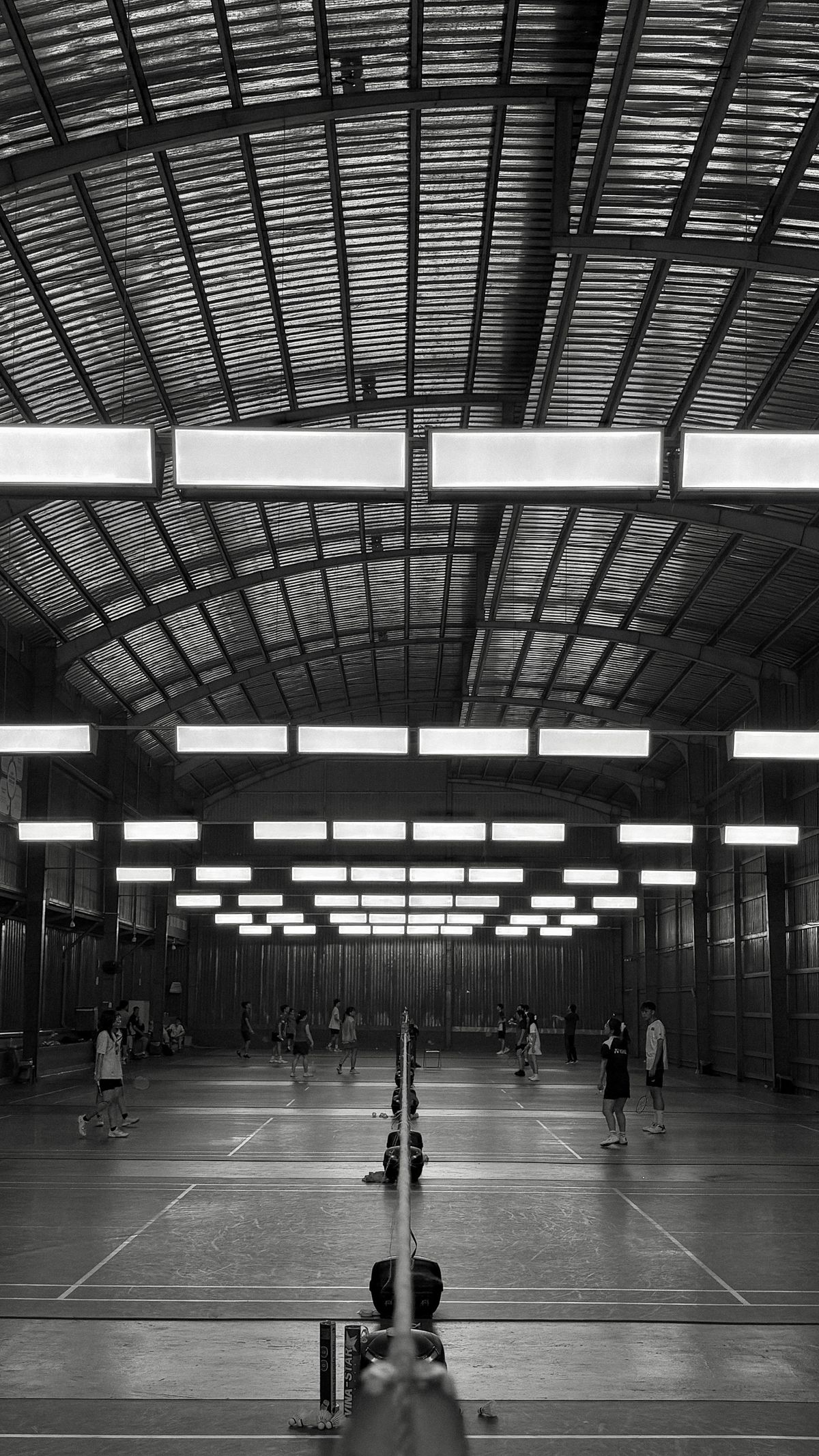 Players competing on a busy indoor badminton court