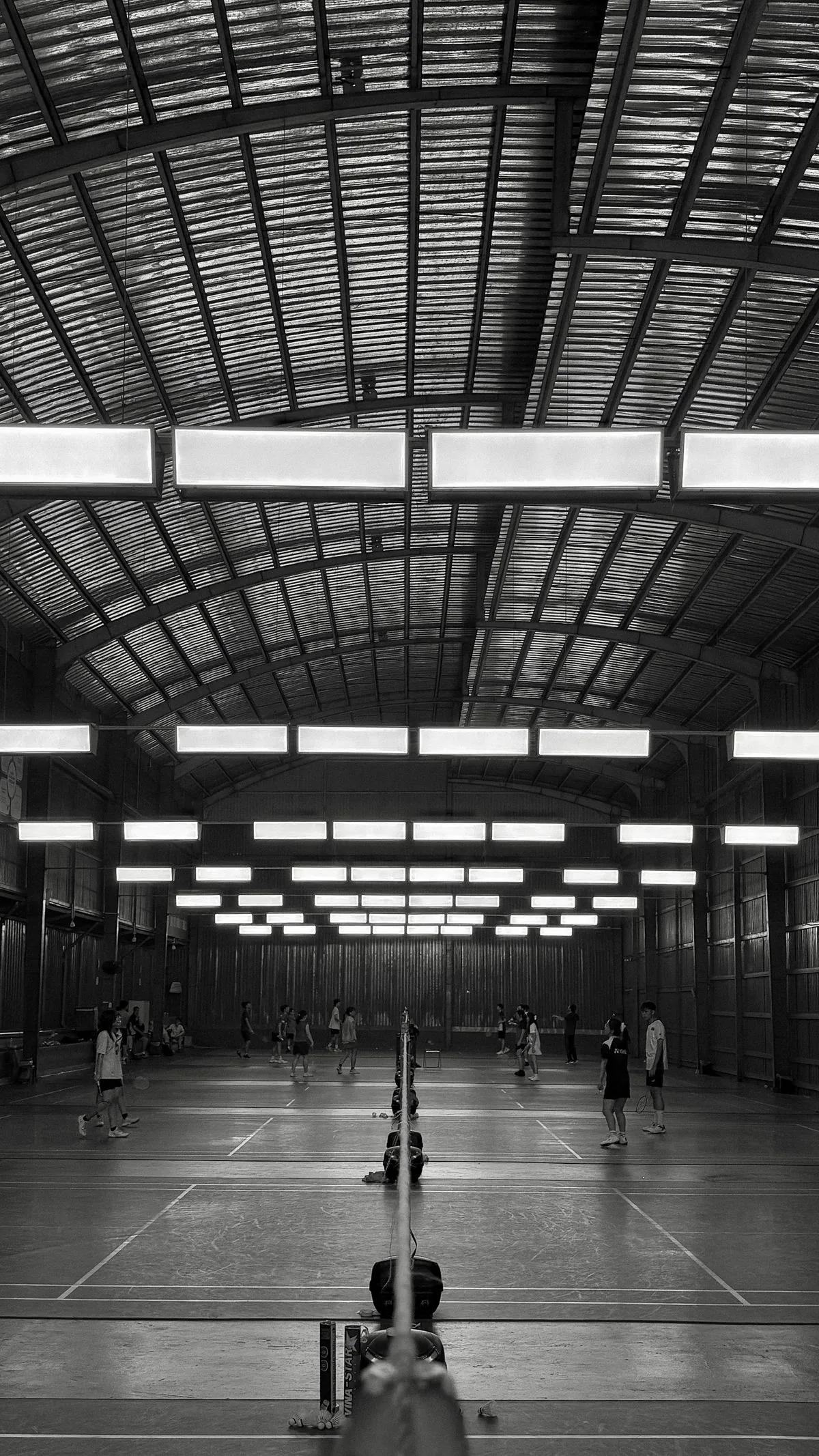 Players competing on a busy indoor badminton court