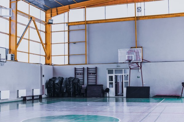 Empty indoor sports hall with a basketball hoop and modern flooring
