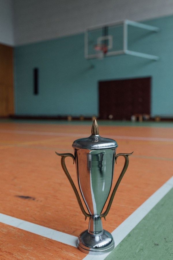 Small trophy standing on a basketball court with the hoop visible in the background