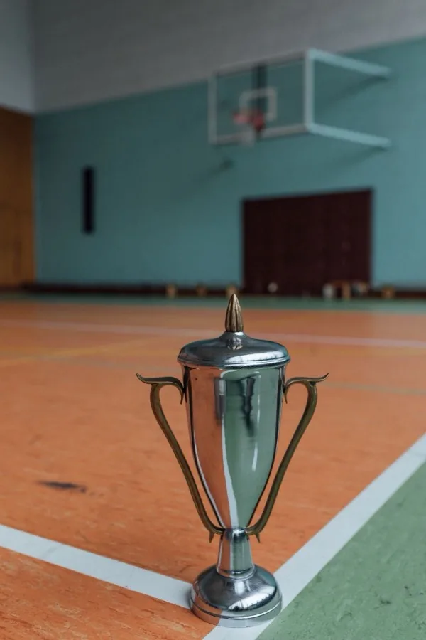 Small trophy standing on a basketball court with the hoop visible in the background