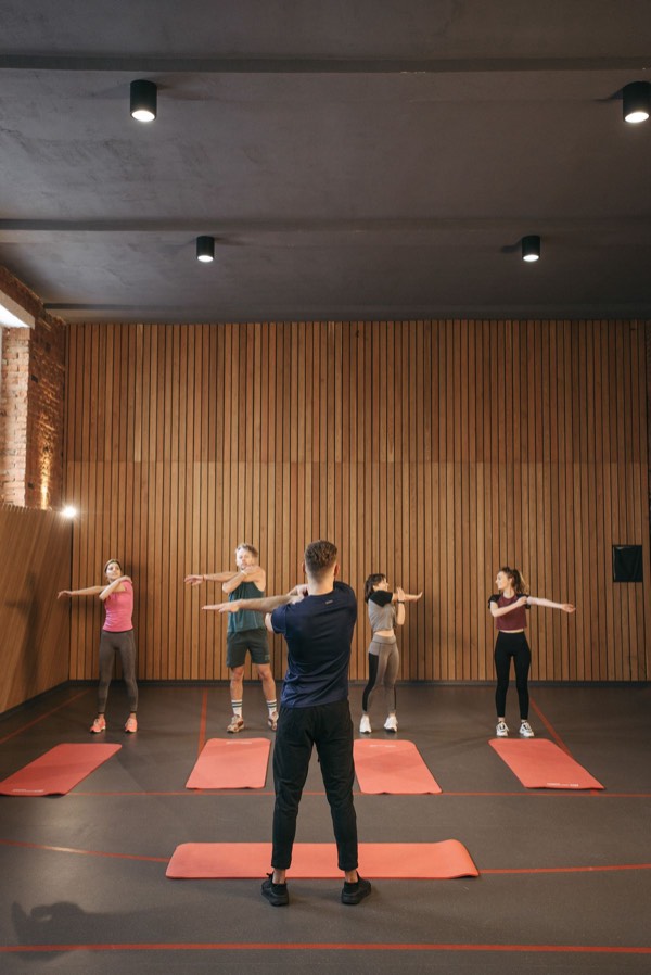 Group fitness class stretching together indoors, led by an instructor