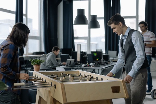 Office employees taking a break to play foosball together