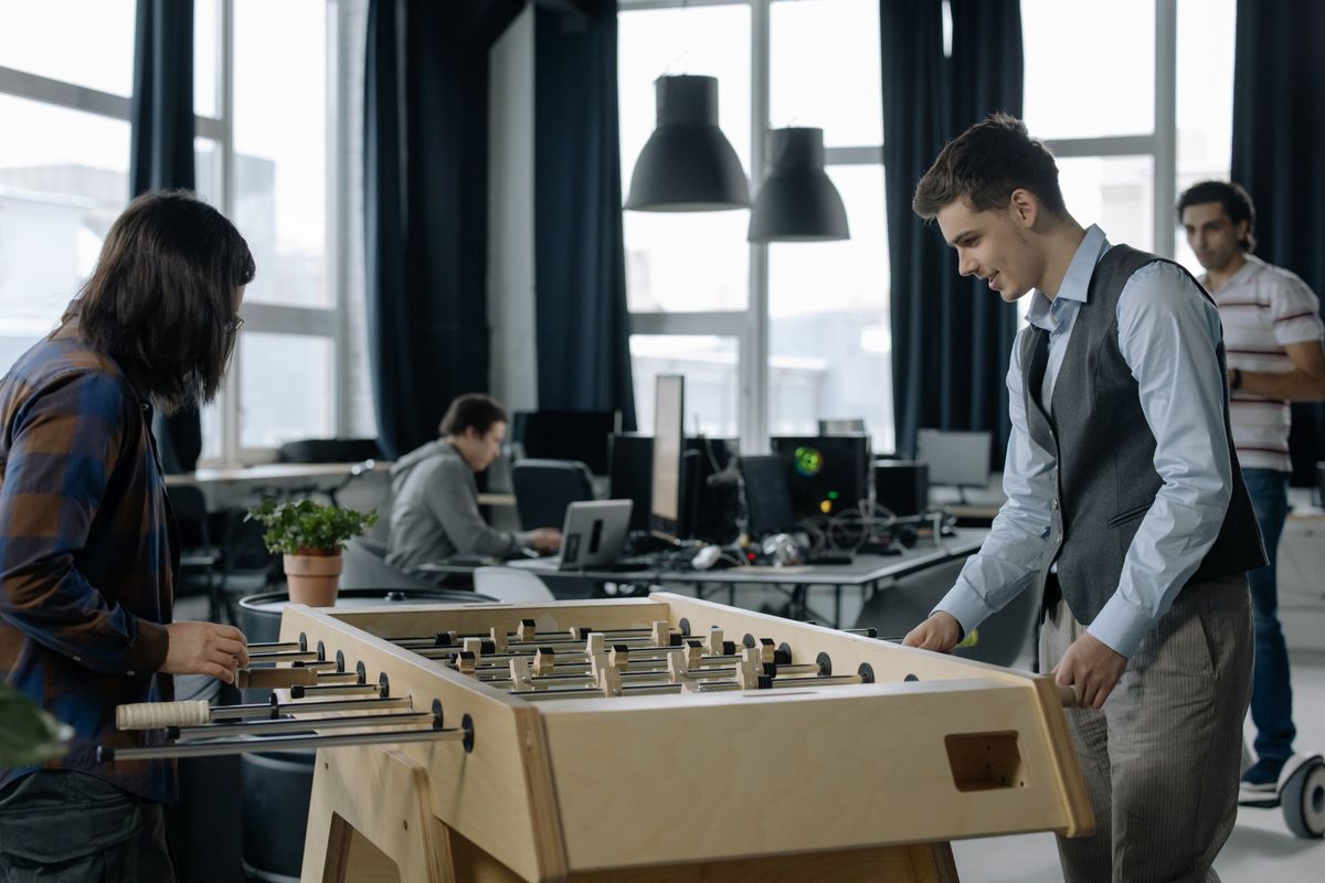 Office employees taking a break to play foosball together