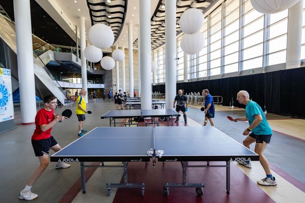 Players competing at a table tennis table inside a modern indoor sports venue