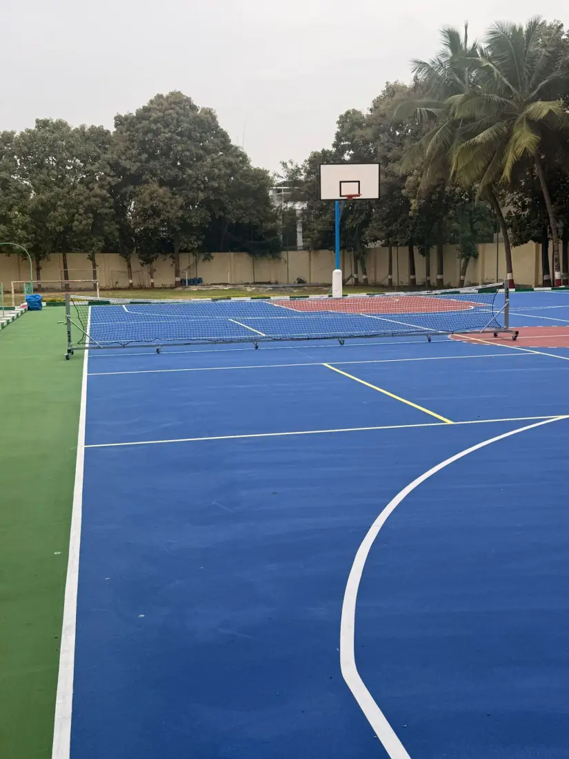 Multi-sport court at Anand Shiksha Kendra with nets set up and basketball hoop in the background