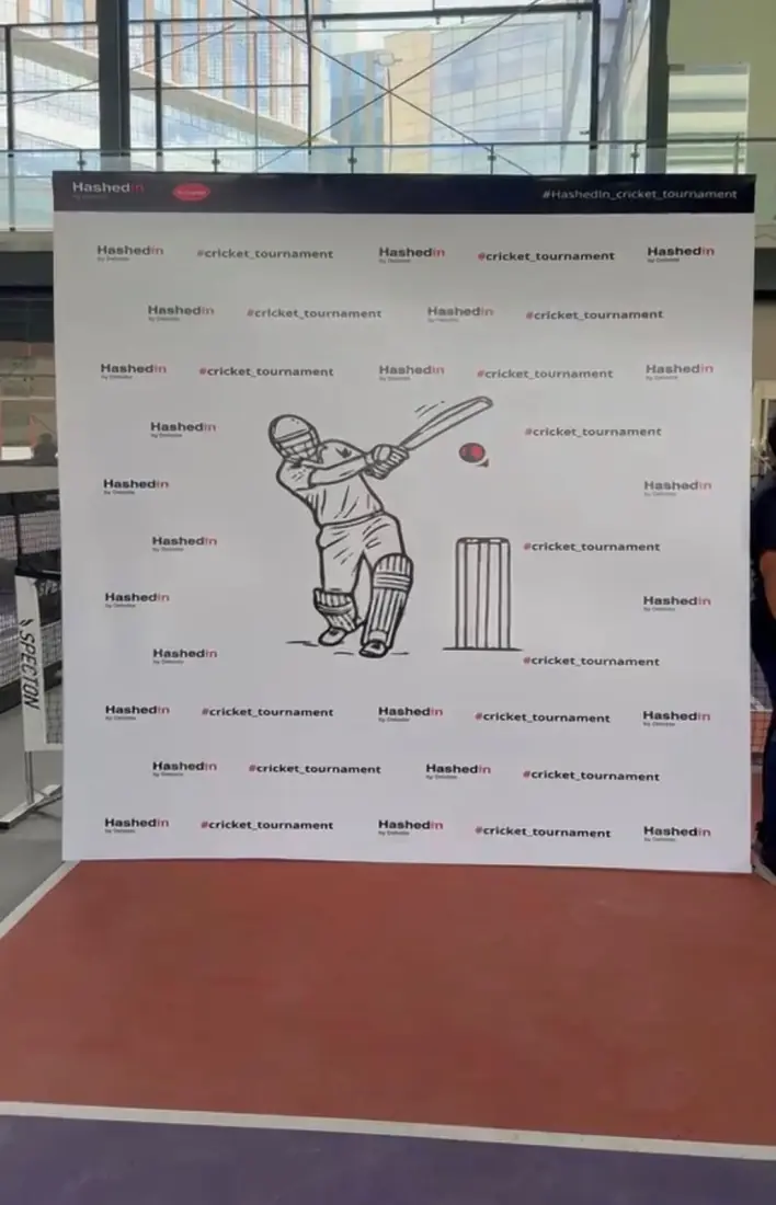 Branded photo backdrop at the HashedIn cricket tournament carrying the client logo and event hashtag